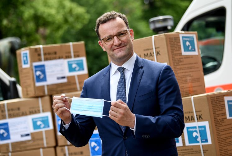 Jens Spahn (CDU), Bundesgesundheitsminister, setzt sich bei der Übergabe der ersten Lieferung von 100 Millionen gespendeten Schutzmasken eine Maske auf.