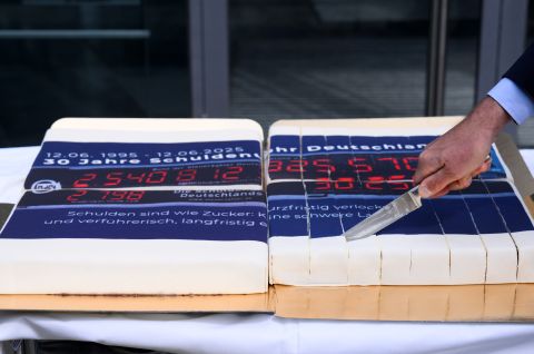 Mann schneidet einen Kuchen mit einer Schuldenuhr-Glasur an