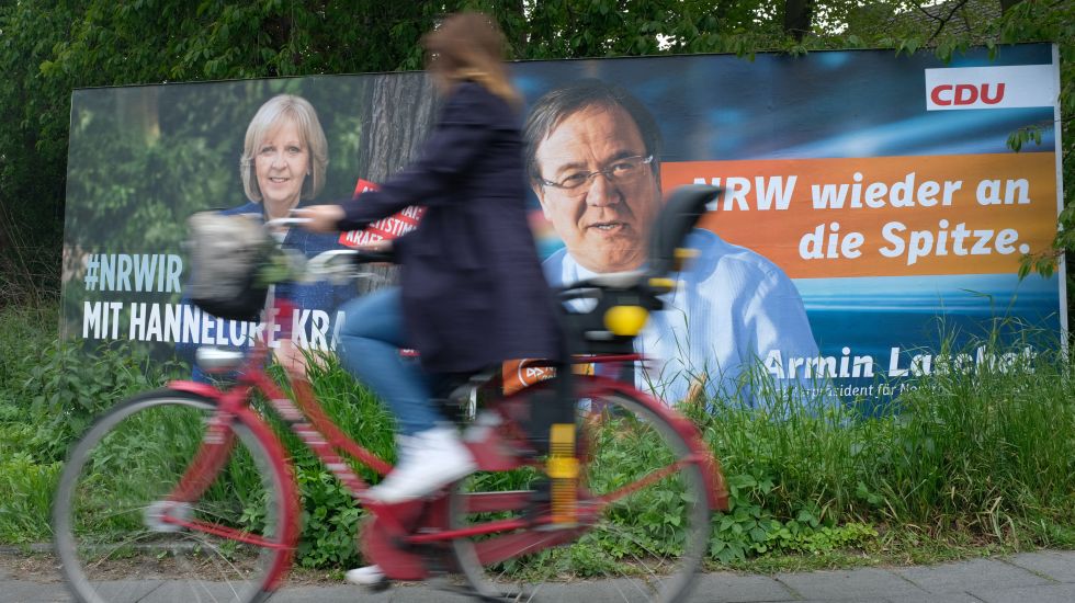 Eine Radfahrerin fährt an Wahlplakaten von Hannelore Kraft und Armin Laschet vorbei