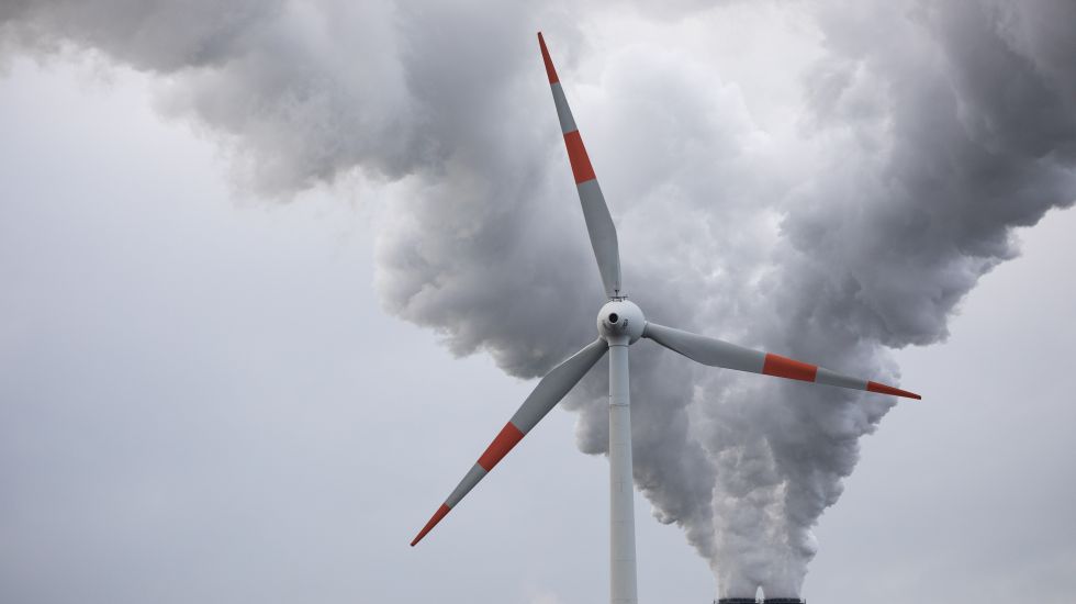 04.11.2019, Hamburg: Abluft steigt aus den Schornsteinen des Kohlekraftwerks Moorburg hinter einem Windrad in den Himmel. Der Energiekonzern Vattenfall betreibt in Hamburg-Moorburg eines der größten und modernsten Kohlekraftwerke Europas.
